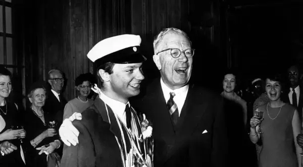 Kung Gustav VI Adolf ler glatt bredvid en student med studentmössa.
