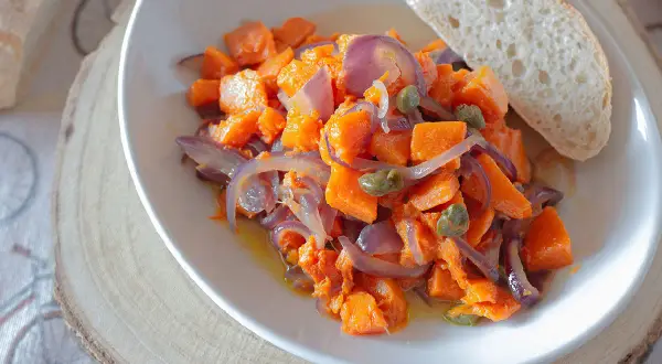 Zucca in padella con cipolle rosse e capperi, un contorno saporito servito con pane fresco.