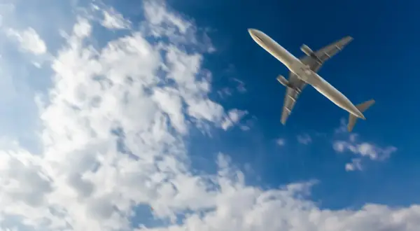 Samolot leci po błękitnym niebie z chmurami. Zastanawiasz się, ile się leci do Marsa Alam?