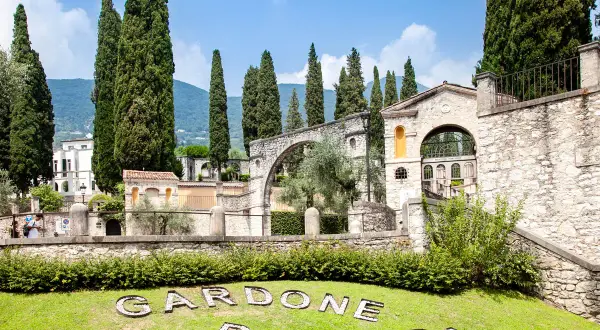 Giardini del Vittoriale, con cipressi svettanti, architetture in pietra e il nome "Gardone Riviera" sull'erba. Ecco cosa vedere al Vittoriale.