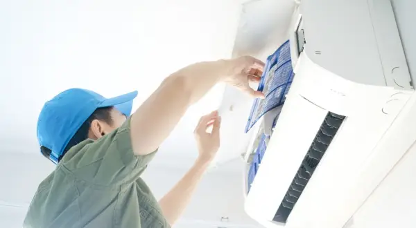 Un technicien nettoie le filtre d'une climatisation, une obligation pour le bailleur afin d'assurer le confort et la qualité de l'air.