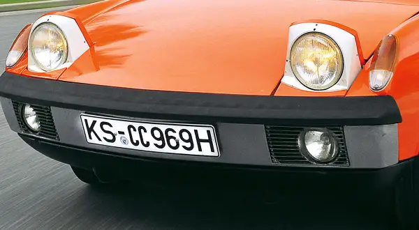 Vorderansicht eines orangefarbenen Oldtimers mit Klappscheinwerfern. Ab wann ist ein Oldtimer steuerfrei?