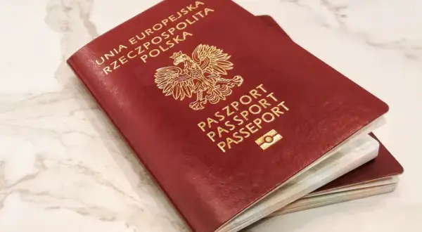 Dwa polskie paszporty, symbole wolności podróżowania i jedne z najsilniejszych paszportów na świecie, leżą na marmurowym blacie.