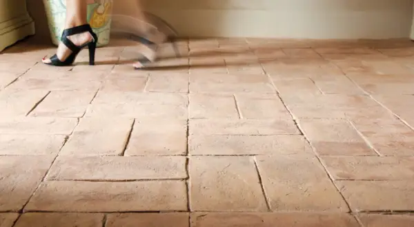 Piedi con sandali neri su un pavimento in cotto. Impara come pulire pavimento in cotto molto sporco per un risultato impeccabile.