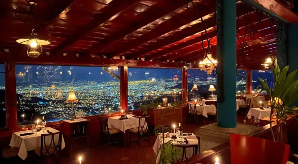 Mesas puestas con velas y vistas a la ciudad iluminada. Un lugar perfecto para saber donde cenar en San José.