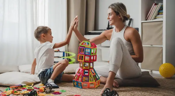 Mama i syn budują wieżę z klocków, ciesząc się wspólnymi zabawami na 3 osoby w domu.