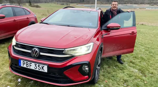Man med halsduk vid en röd VW Taigo. Bilen är redo för ett vw taigo test i svensk natur.