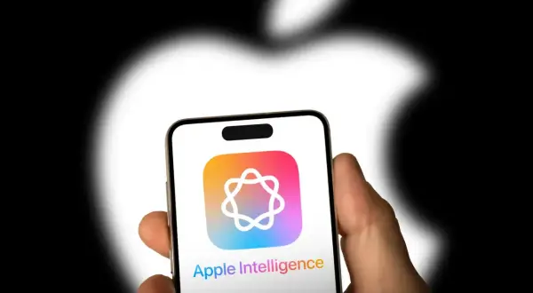 Dłoń trzyma iPhone'a z logo Apple Intelligence. Tło to rozmyte logo Apple.