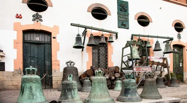 Antiche agnone campane della Pontificia Fonderia Marinelli, alcune appese, altre a terra, con un gatto curioso tra le più grandi.
