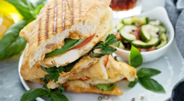 Pyszne panini z kurczakiem, pomidorem i bazylią, podane z sałatką z ogórka. Idealne na szybki lunch.