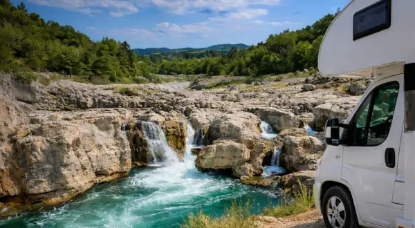 Wohnmobil am tosenden Wasserfall, ein wahres Naturwunder Deutschland. Türkises Wasser stürzt über Felsen, umgeben von grünen Hügeln.