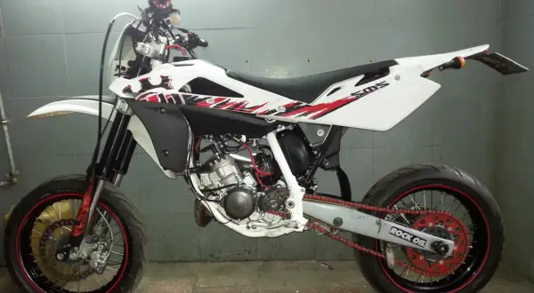 Husqvarna SMS 125 w białej odsłonie z czerwono-czarnymi grafikami, gotowy do jazdy po mieście i torze.
