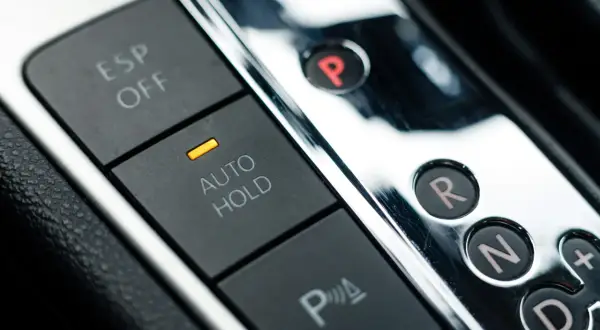 Przyciski ESP OFF, AUTO HOLD i P w samochodzie. Dźwignia zmiany biegów z literami P, R, N, D i przyciskiem "+", sugerująca tryb tiptronic.