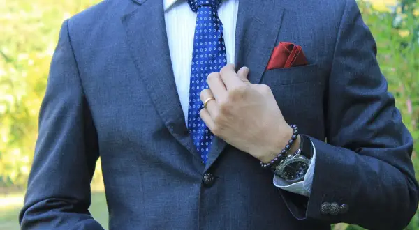 Mann im grauen Anzug mit blauer Krawatte, die perfekt zu seinem blauen Anzug passt. Rotes Einstecktuch.