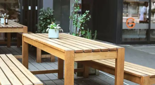 Ensemble de mobilier d'extérieur en bois, table et bancs, dont le traitement met en valeur la beauté naturelle du bois.