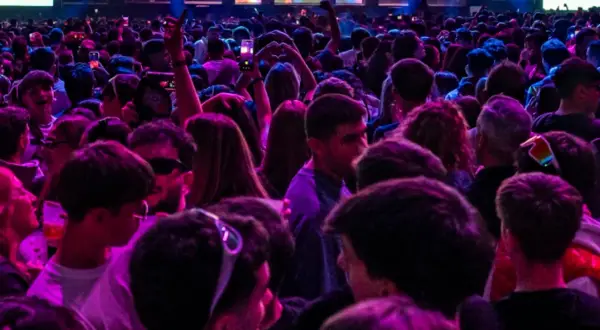 Multitud vibrante en un concierto, luces de neón y un gran cartel de "Espacio Zity" al fondo.
