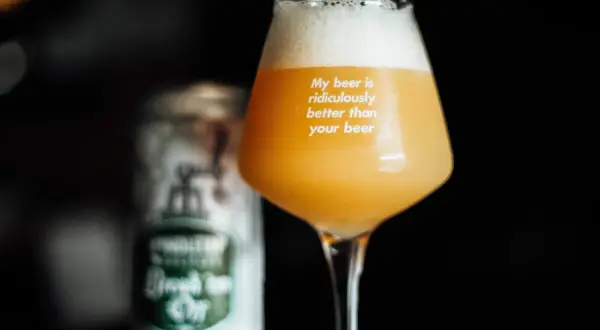 Bicchiere con birra neipa dal colore dorato e schiuma abbondante. Sul vetro la scritta "My beer is ridiculously better than your beer". Sullo sfondo una lattina sfocata.
