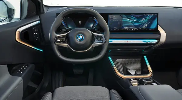 Interni moderni con volante, cruscotto digitale e ampio schermo per il sistema infotainment. Dettagli luminosi e finiture eleganti.