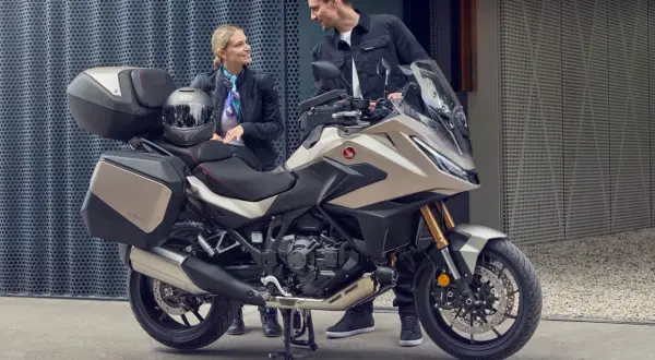Pareja sonriente junto a una Honda NT 1100, lista para viajar. Opiniones positivas sobre su comodidad y diseño.