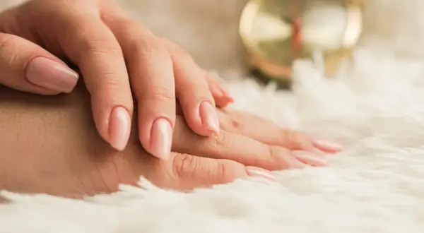 Delikatne dłonie z różowym, naturalnym lakierem. Idealny manicure biologiczny dla każdej kobiety.