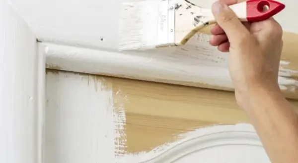 Application de peinture blanche sur un meuble en bois, montrant qu'il est possible de peindre métal sans décaper.