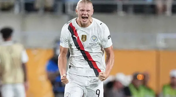 Piłkarz Manchesteru City, Erling Haaland, w białej koszulce z czerwono-czarnym pasem, świętuje bramkę.