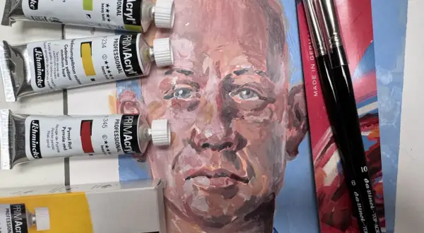 Acrylbilder-Set mit Farben, Pinseln und einem unfertigen Porträt.