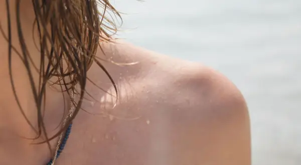 Schulter mit Wassertropfen und nassem Haar. Warum werde ich nicht braun?