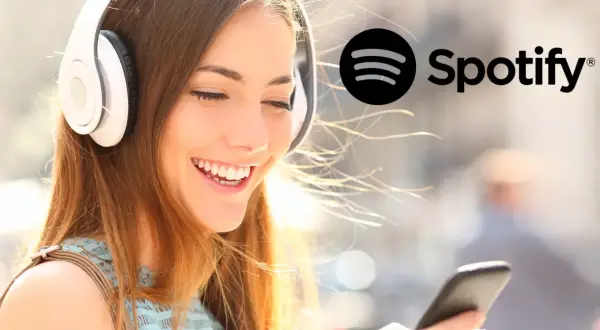 Uśmiechnięta dziewczyna w słuchawkach słucha muzyki na Spotify. Dowiedz się, jak zmienić nazwę użytkownika na Spotify.