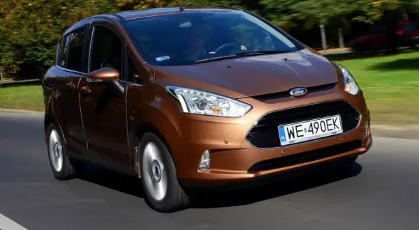 Brązowy Ford B-Max jedzie po drodze, za nim drzewa w jesiennych barwach.