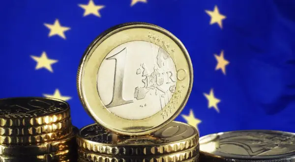 Monety euro na tle flagi UE. Pamiętasz, w którym roku weszło euro w Niemczech?