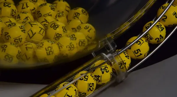 Żółte kulki z numerami w maszynie losującej, które wyłonią zwycięzców gry Eurojackpot.