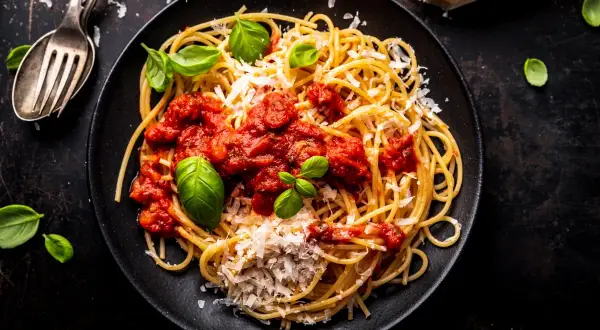 Talerz spaghetti z sosem pomidorowym, parmezanem i bazylią.