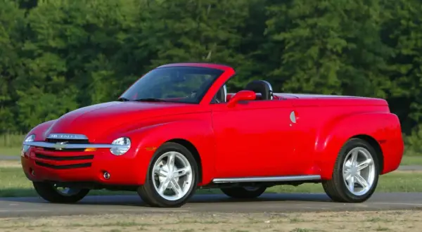 Czerwony Chevrolet SSR z otwartym dachem, gotowy na letnią przejażdżkę pośród zieleni.