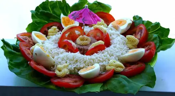 Salade de riz thon festive, garnie d'œufs durs, tomates, mayonnaise et d'un petit parasol rose. Un délice coloré !