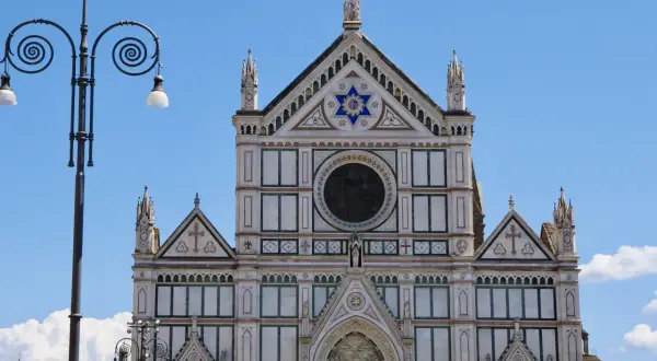Fasada katedry Santa Maria del Fiore we Florencji, ozdobiona mozaikami i rzeźbami, lśni w słońcu.