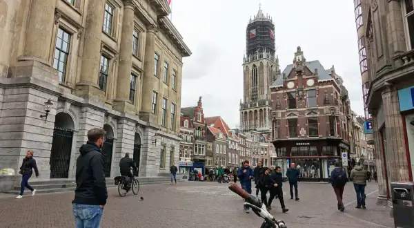Menschen spazieren durch die Kopfsteinpflasterstraßen der utrecht altstadt, vorbei an historischen Gebäuden und dem Domturm.