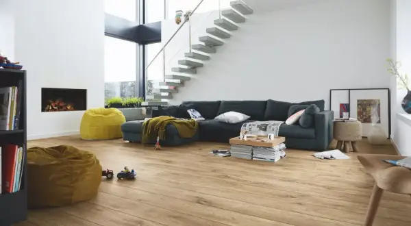 Salon moderne avec canapé, cheminée, poufs et escalier flottant. Le parquet flottant, d'une épaisseur idéale, réchauffe l'espace.