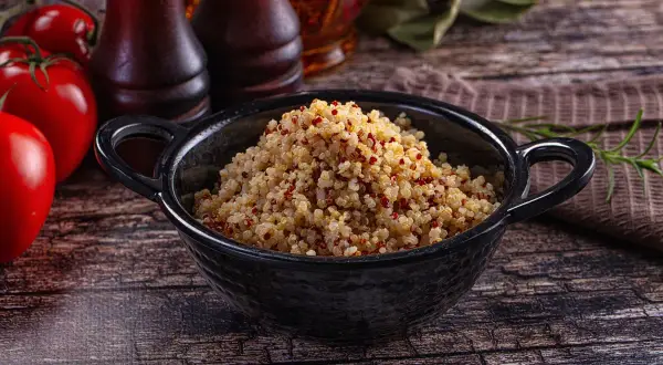 Quinoa cotta in una ciotola nera, pronta per essere gustata. Ecco come cuocere la quinoa per un piatto sano e gustoso.