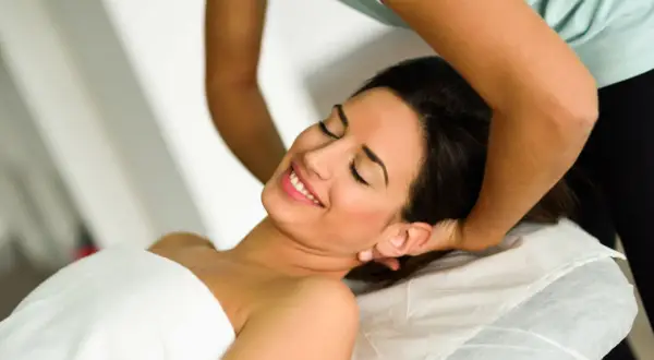 Donna sorride durante una seduta di terapia cranio sacrale. Non si segnalano effetti collaterali negativi, solo benessere.