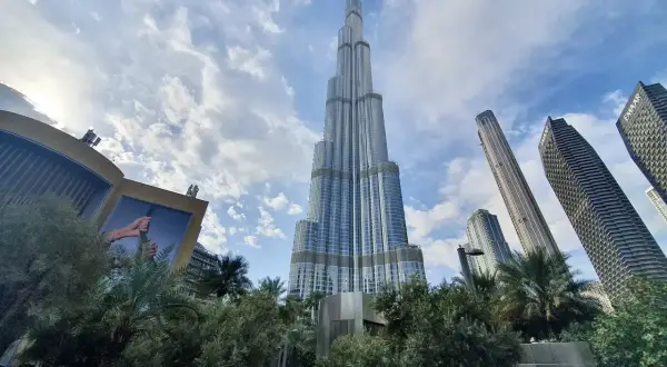 Majestatyczny Burj Khalifa w Dubaju wznosi się ku niebu, otoczony nowoczesnymi wieżowcami i zielenią.