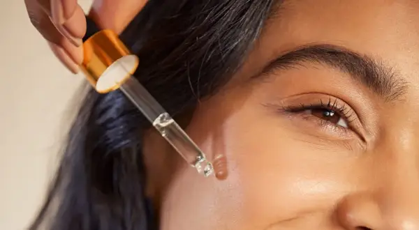 Kropla serum z pipetki zbliża się do twarzy, obiecując widoczne retinol efekty.