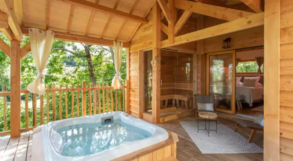 Terrasse en bois avec jacuzzi, sauna et chambre. Une invitation à une nuit insolite au nord, au cœur de la nature.
