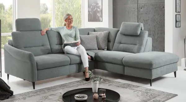 Frau liest auf einem gemütlichen Ecksofa mit verstellbaren Kopfstützen. Die tiefe **sitztiefe sofa** lädt zum Entspannen ein.