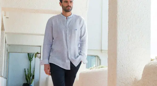Uomo con camicia a maniche lunghe, dal taglio comodo, con la **lunghezza camicia uomo fuori pantaloni** che crea un look casual.