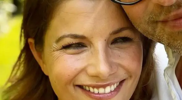 Agnieszka Sienkiewicz uśmiecha się, przytulona do swojego męża, który ma zarost i okulary.