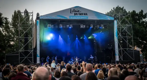 Koncert na Letnich Brzmieniach we Wrocławiu, scena z zespołem i tłum widzów.