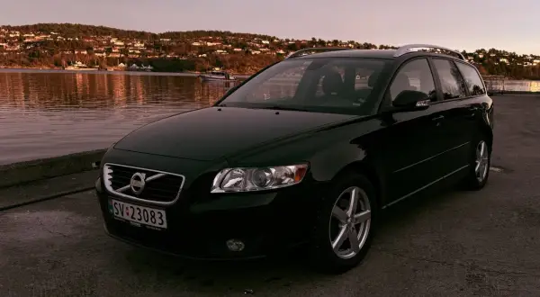 Svart Volvo V50 vid vattnet i solnedgången. Denna bilmodell är känd för sina pålitliga volvo v50 motorer.