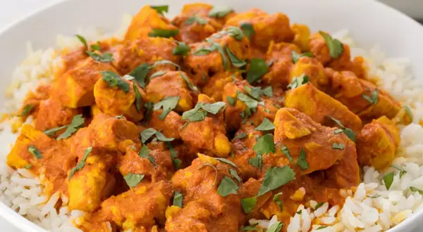 En skål med fluffigt ris toppad med saftig kyckling i en krämig, orange currysås. Strössel av färsk koriander ger en härlig touch till denna skolans kyckling curry.