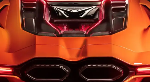 Pomarańczowy Lamborghini Revuelto z widocznym silnikiem i czerwonym podświetleniem.